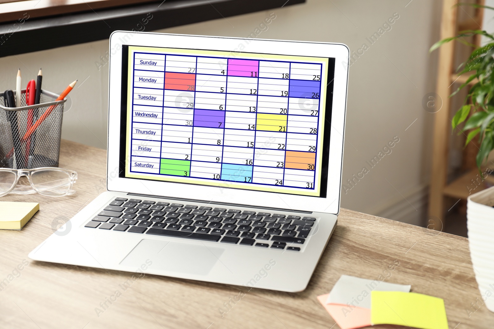 Photo of Modern laptop with calendar app at table in office