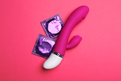 Photo of Vibrator and condoms on pink background, top view. Sex game