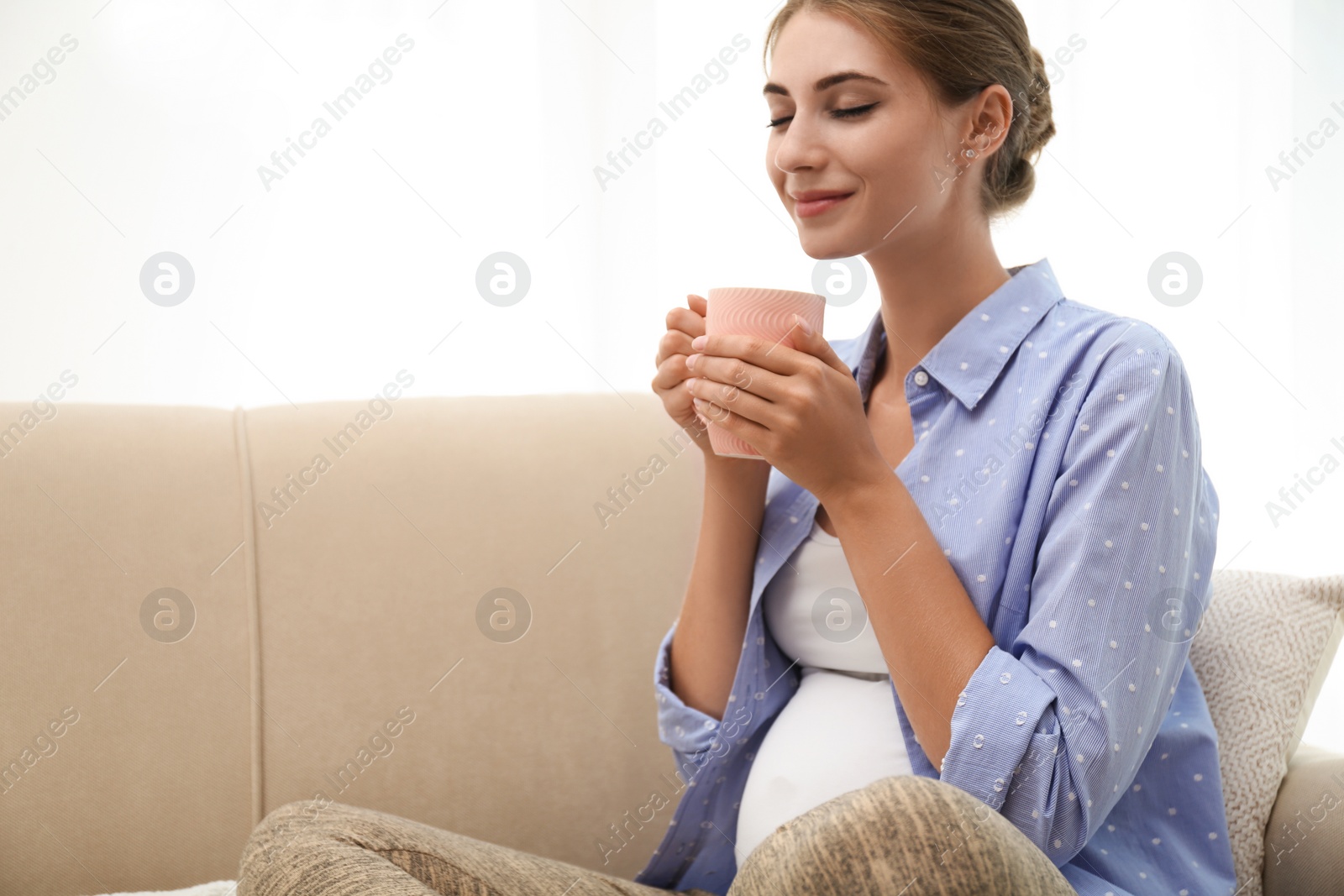 Photo of Happy pregnant woman drinking tea at home