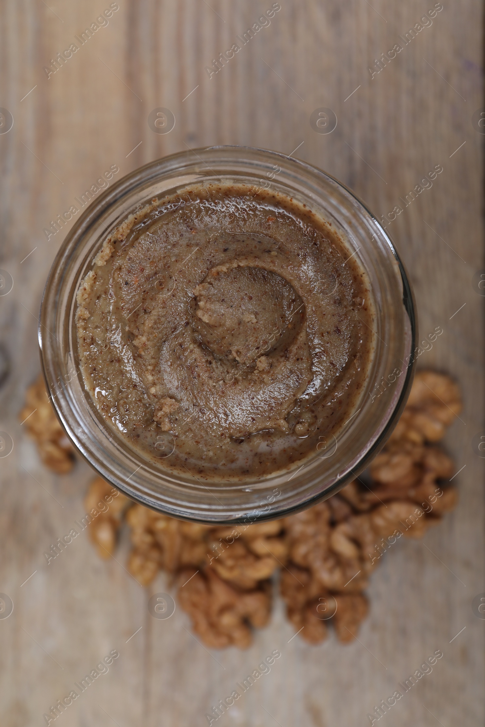 Photo of Tasty walnut nut paste in jar on table, top view