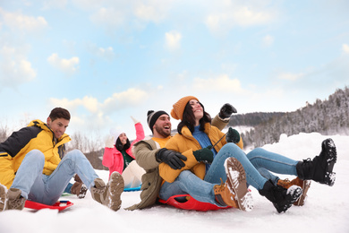 Group of friends having fun and sledding on snow. Winter vacation