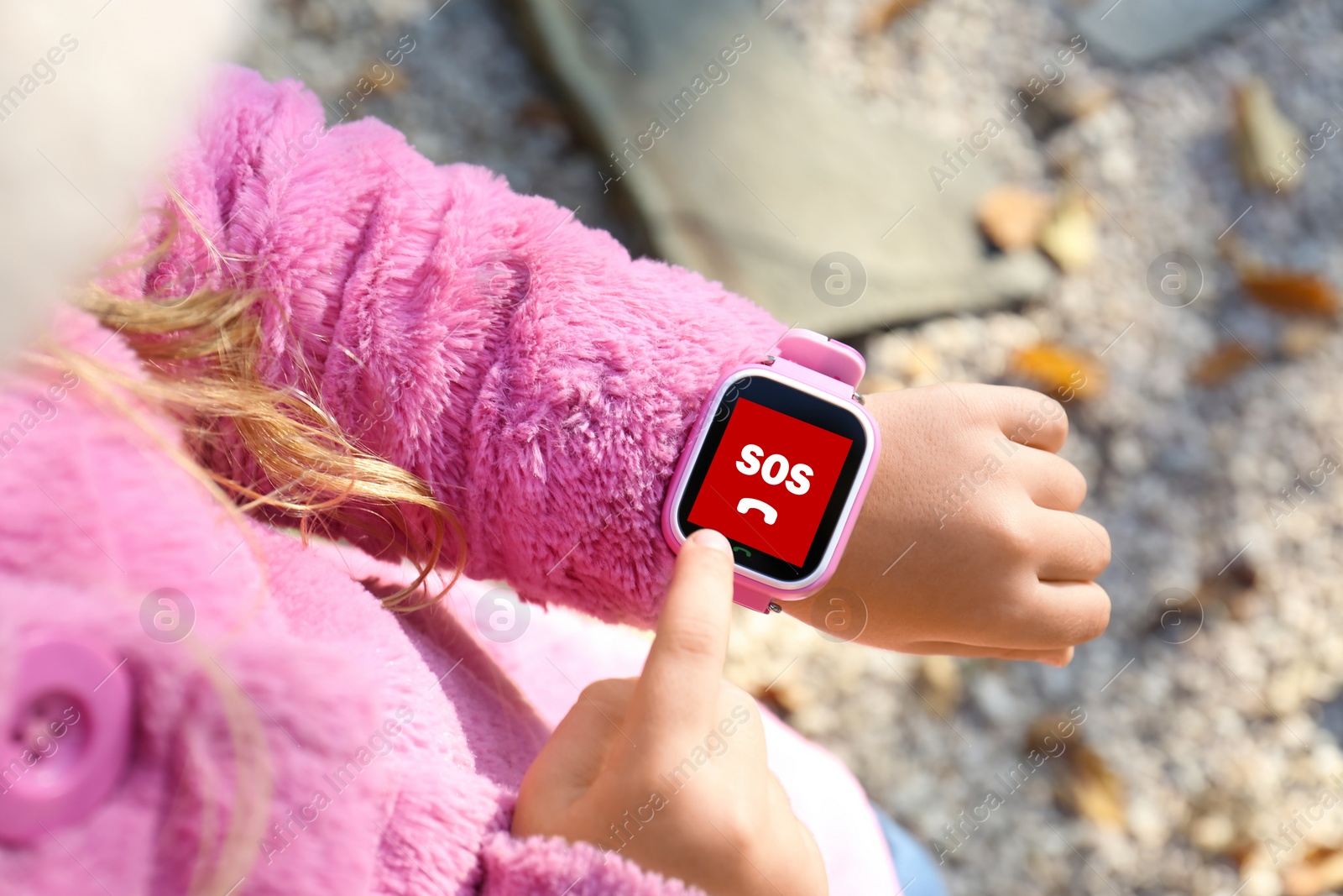 Image of Little girl using SOS function on smartwatch outdoors, closeup