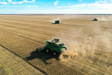 Photo of Modern combine harvester working in field on sunny day. Agriculture industry