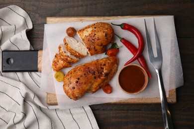 Photo of Baked chicken fillets, chili peppers and marinade on wooden table, top view