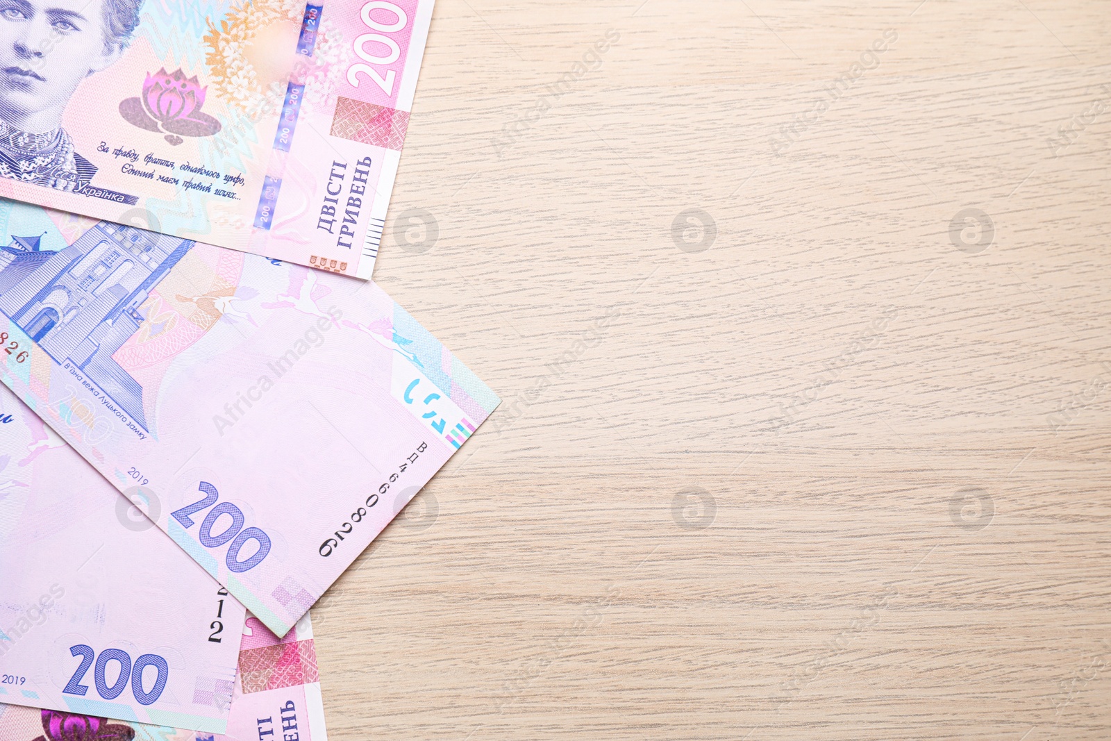 Photo of Ukrainian money on wooden background, flat lay. Space for text