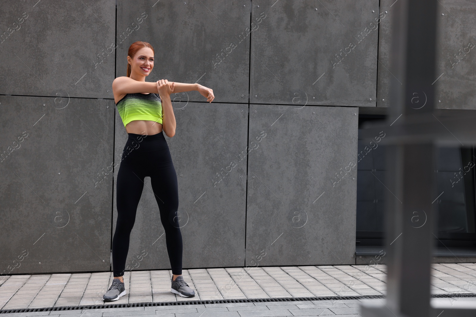 Photo of Beautiful woman in gym clothes doing exercises on street