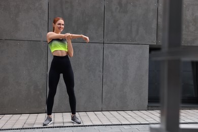 Beautiful woman in gym clothes doing exercises on street