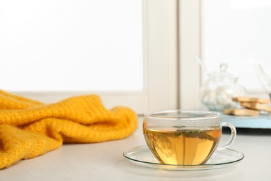 Photo of Cup of fresh tea on windowsill indoors, space for text. Winter drink