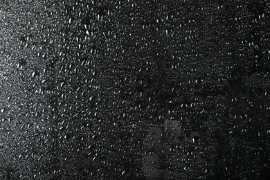 Photo of Glass with rain drops against dark background