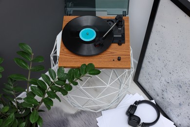 Stylish turntable with vinyl record on coffee table in room, above view