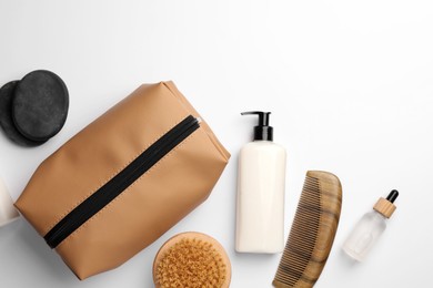 Photo of Compact toiletry bag, cosmetic products, comb and spa stones on white background, flat lay. Space for text