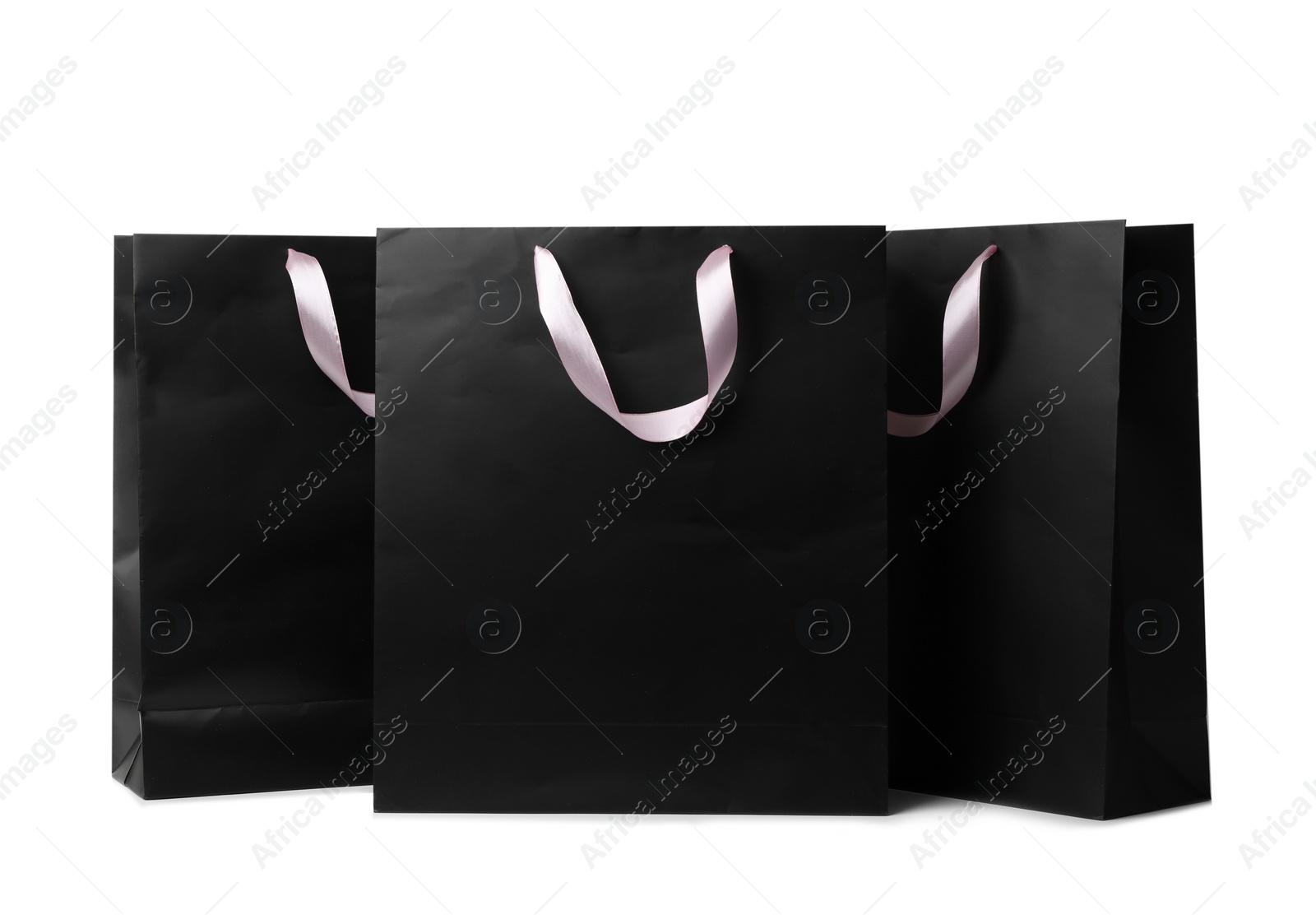 Photo of Paper shopping bags with ribbon handles on white background. Mockup for design