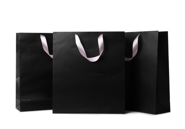 Paper shopping bags with ribbon handles on white background. Mockup for design