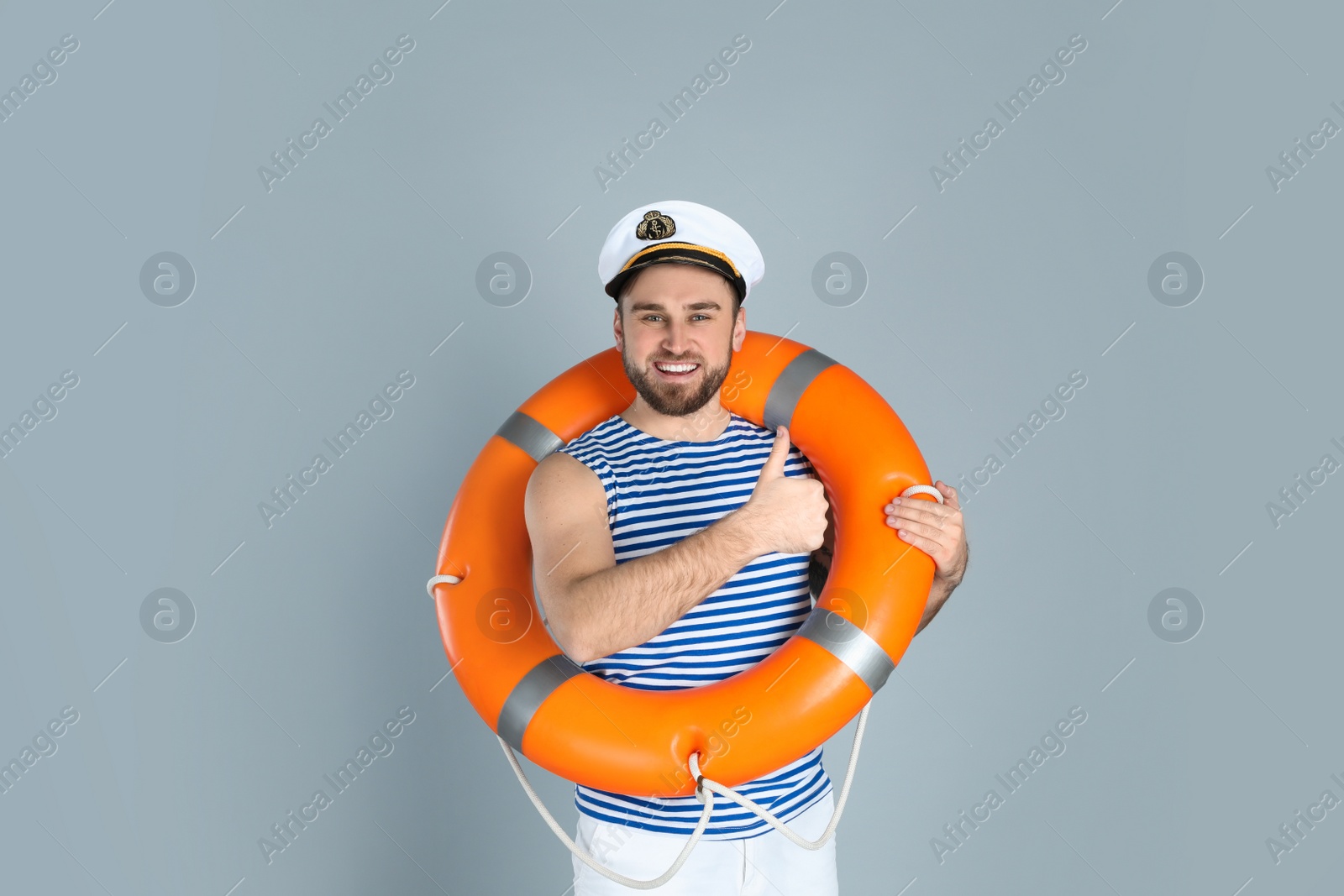 Photo of Happy sailor with ring buoy on light grey background