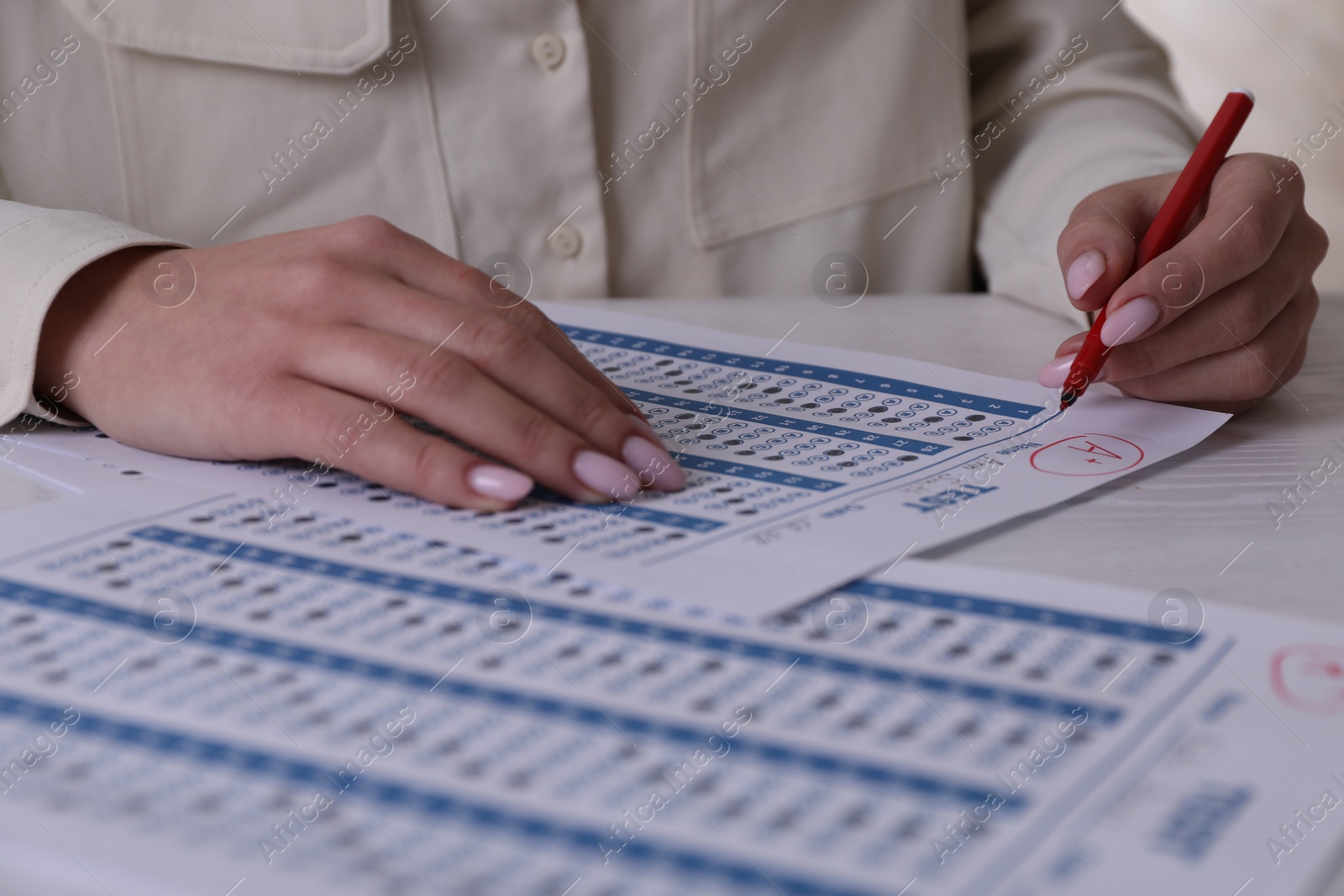 Photo of School grade. Teacher writing letter A with plus symbol on answer sheet at white table, closeup