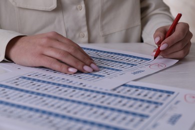 Photo of School grade. Teacher writing letter A with plus symbol on answer sheet at white table, closeup