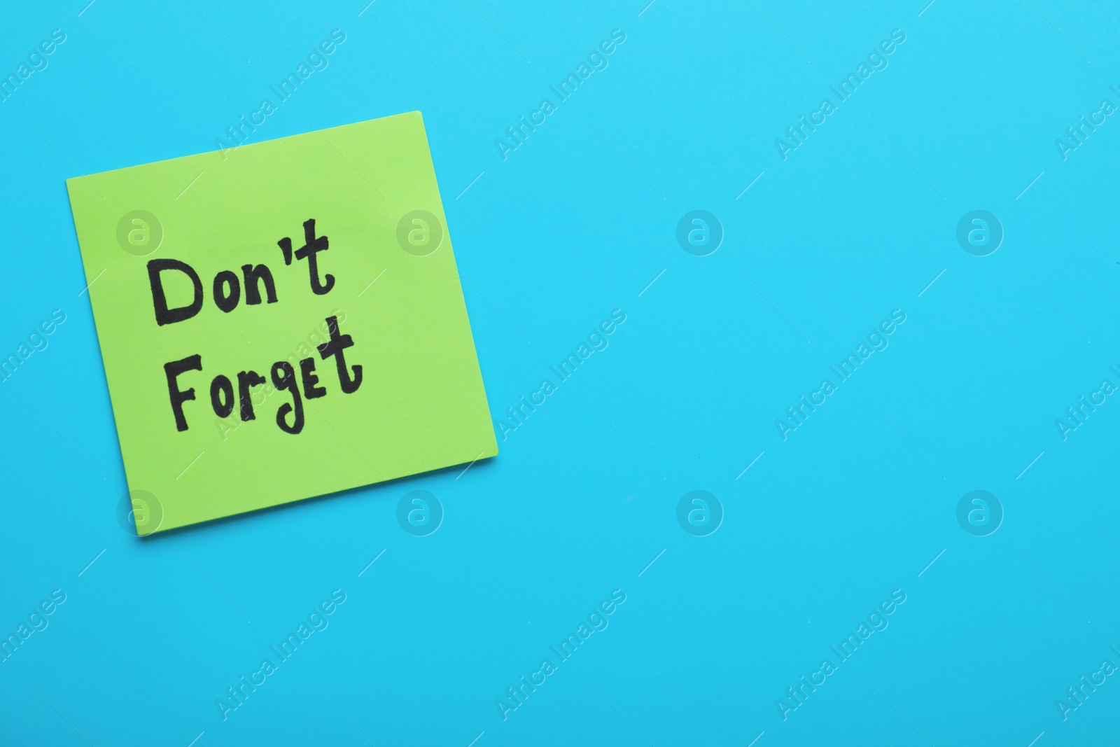 Photo of Paper note with phrase Don' t Forget on blue background, top view. Space for text