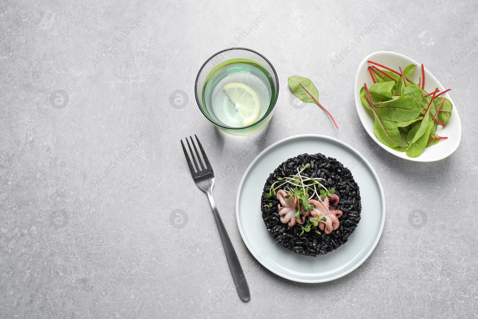 Photo of Delicious black risotto with seafood served on light grey table. Space for text