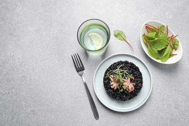 Delicious black risotto with seafood served on light grey table. Space for text