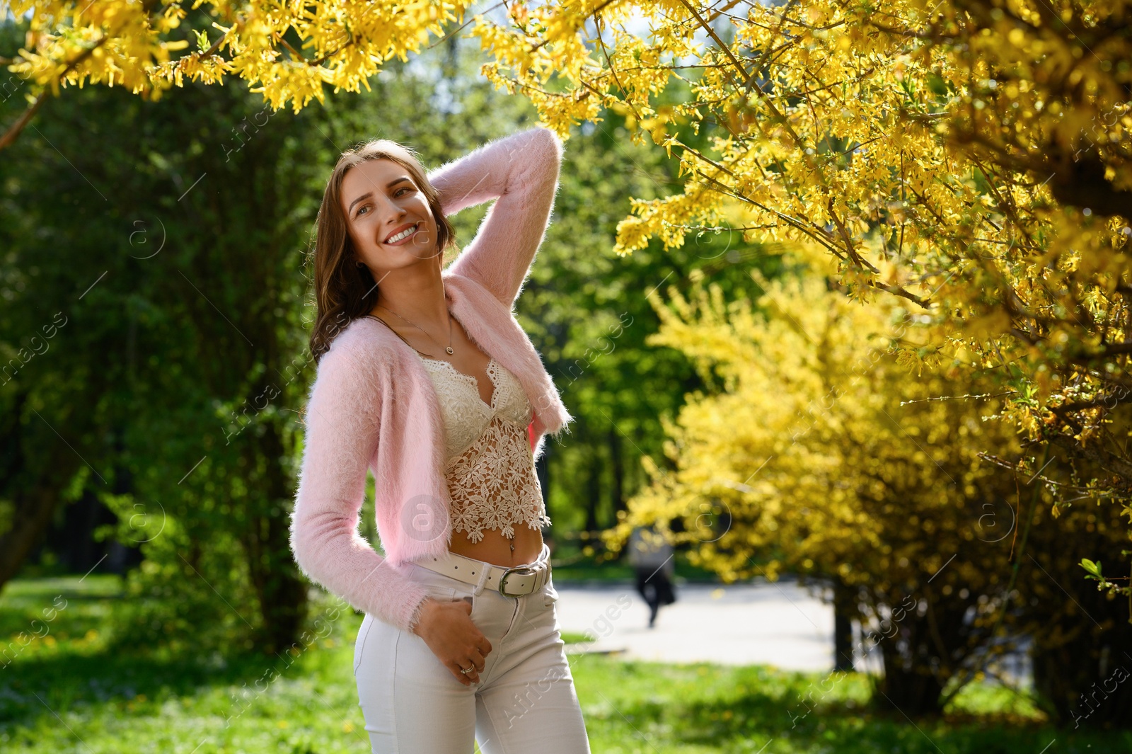 Photo of Beautiful young woman near blossoming shrub on spring day, space for text