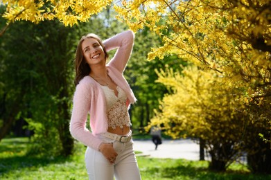 Beautiful young woman near blossoming shrub on spring day, space for text