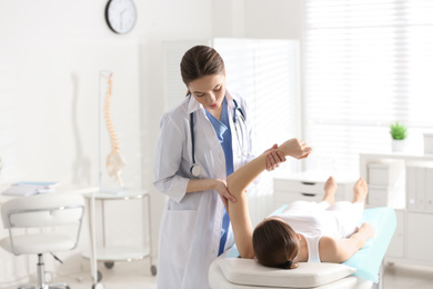 Photo of Female orthopedist examining patient's arm in clinic