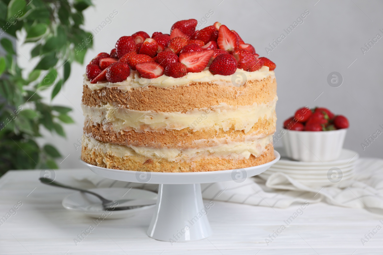 Photo of Tasty cake with fresh strawberries served on white wooden table