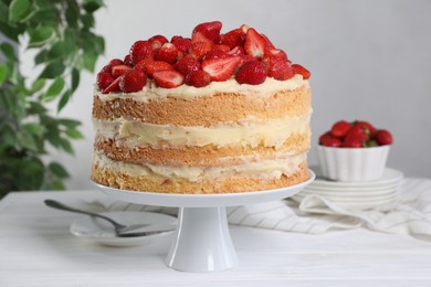 Tasty cake with fresh strawberries served on white wooden table