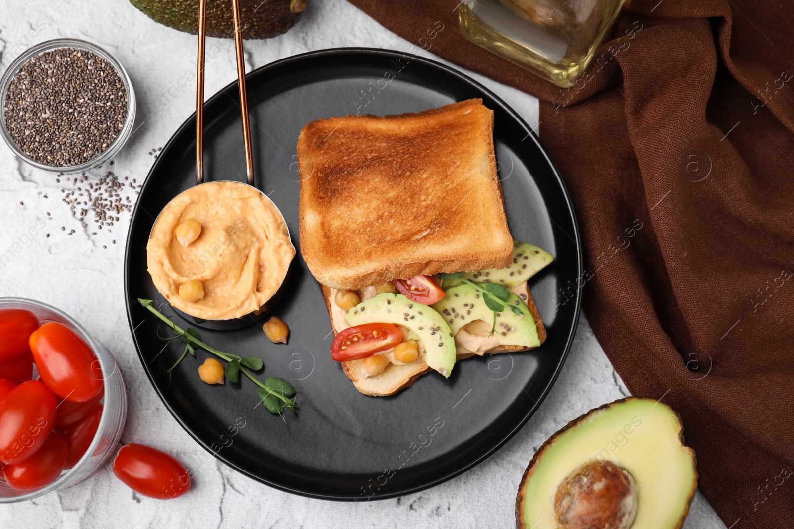 Photo of Delicious sandwich with hummus and vegetables, ingredients on white textured table, flat lay