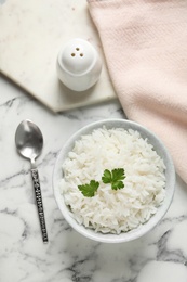 Photo of Bowl of tasty cooked rice with parsley served on table, flat lay