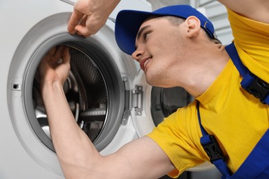 Photo of Smiling plumber checking door gasket of washing machine