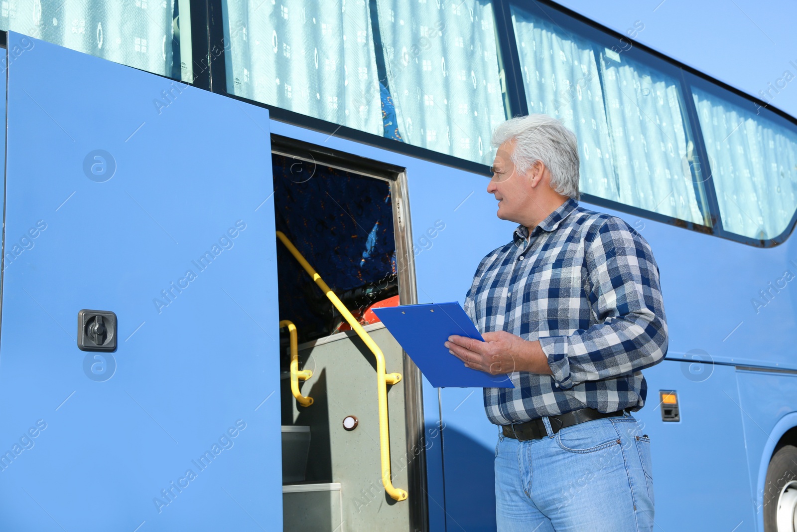 Photo of Professional driver with clipboard near bus. Passenger transportation