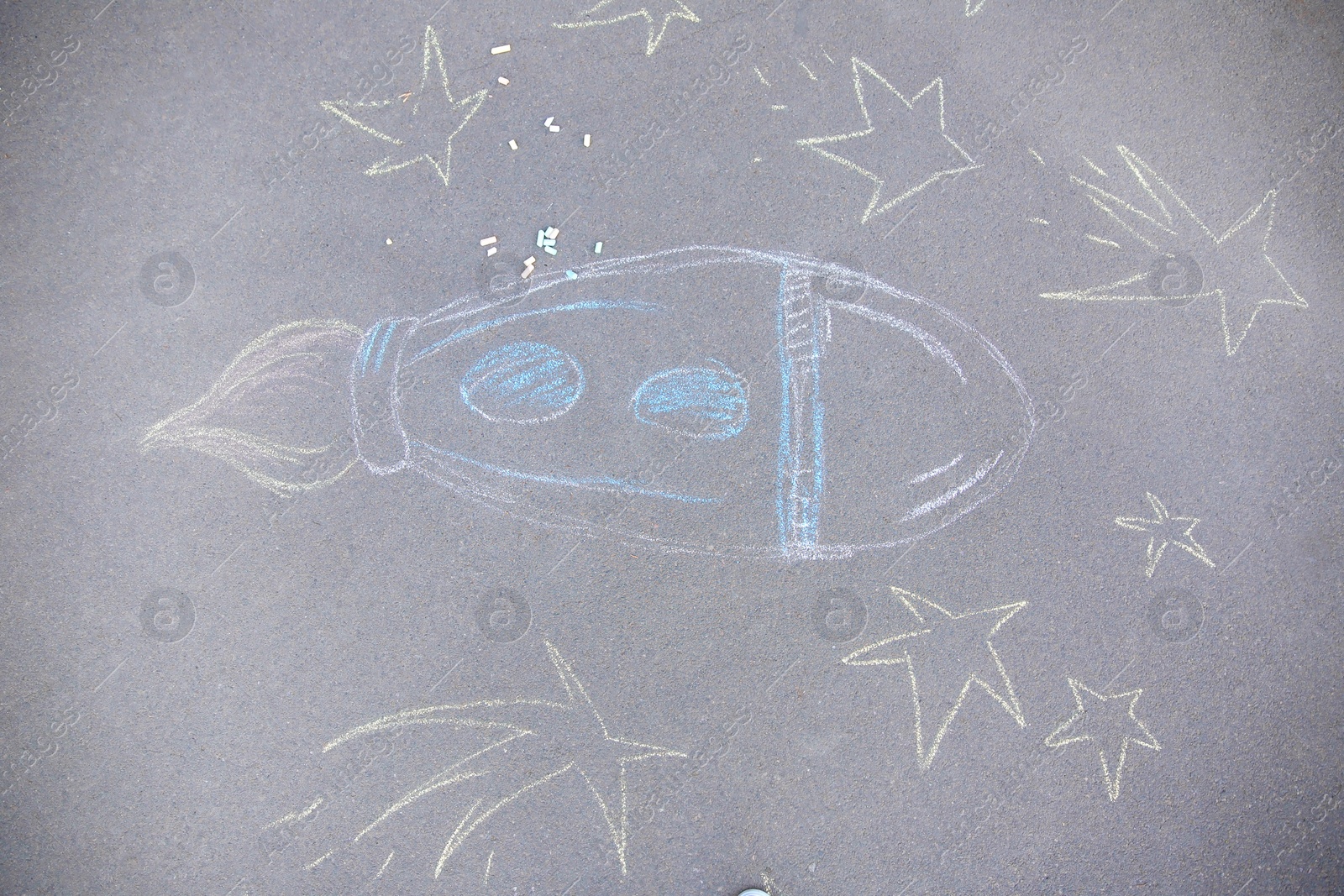Photo of Child's chalk drawing of rocket on asphalt, top view
