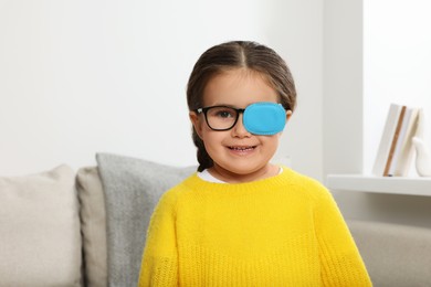 Photo of Happy girl with nozzle on glasses for treatment of strabismus in room