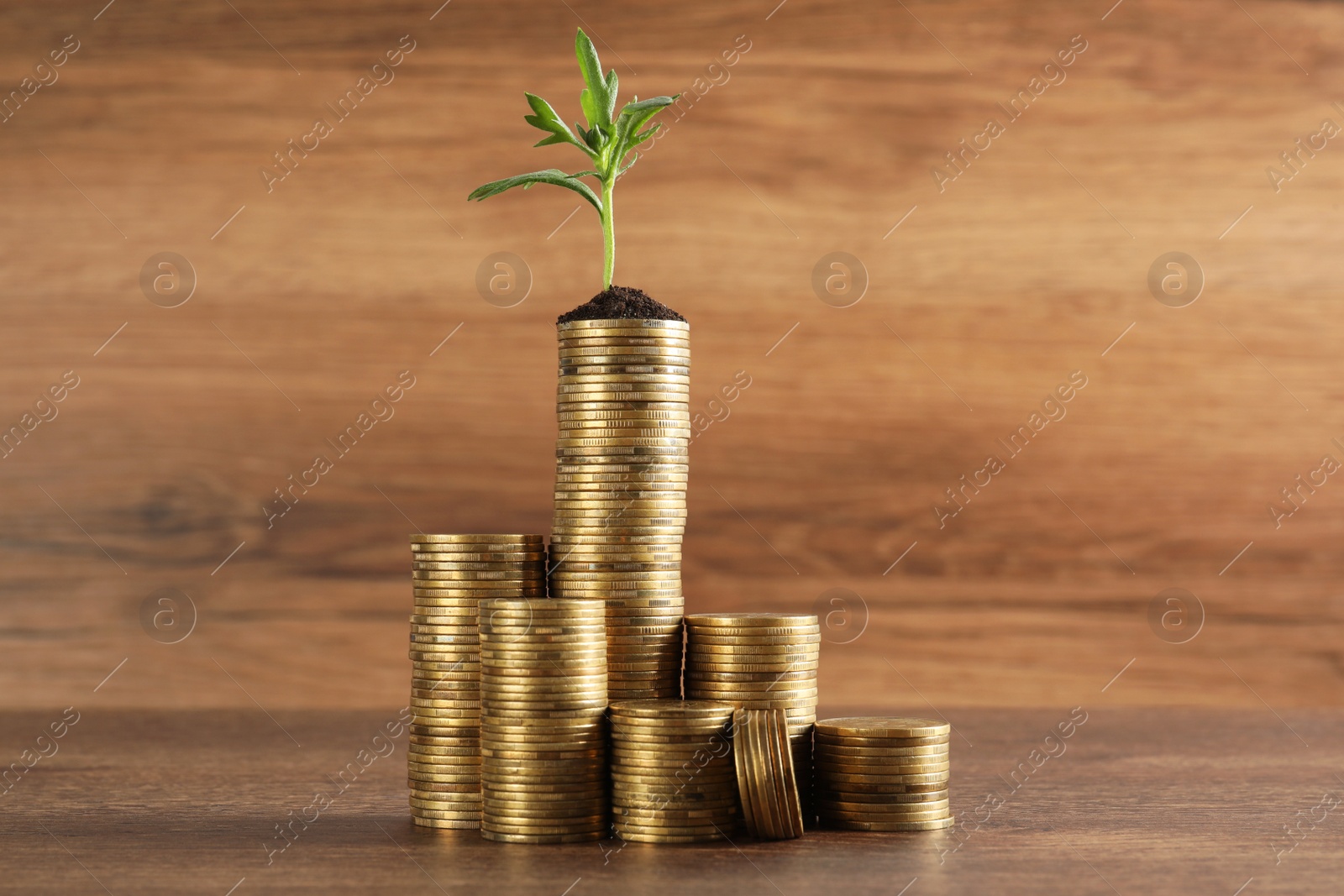 Photo of Stacked coins and green sprout on wooden table. Investment concept