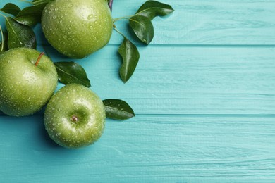 Photo of Fresh ripe green apples with water drops on turquoise wooden table, flat lay. Space for text