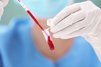 Scientist dripping blood into test tube in laboratory