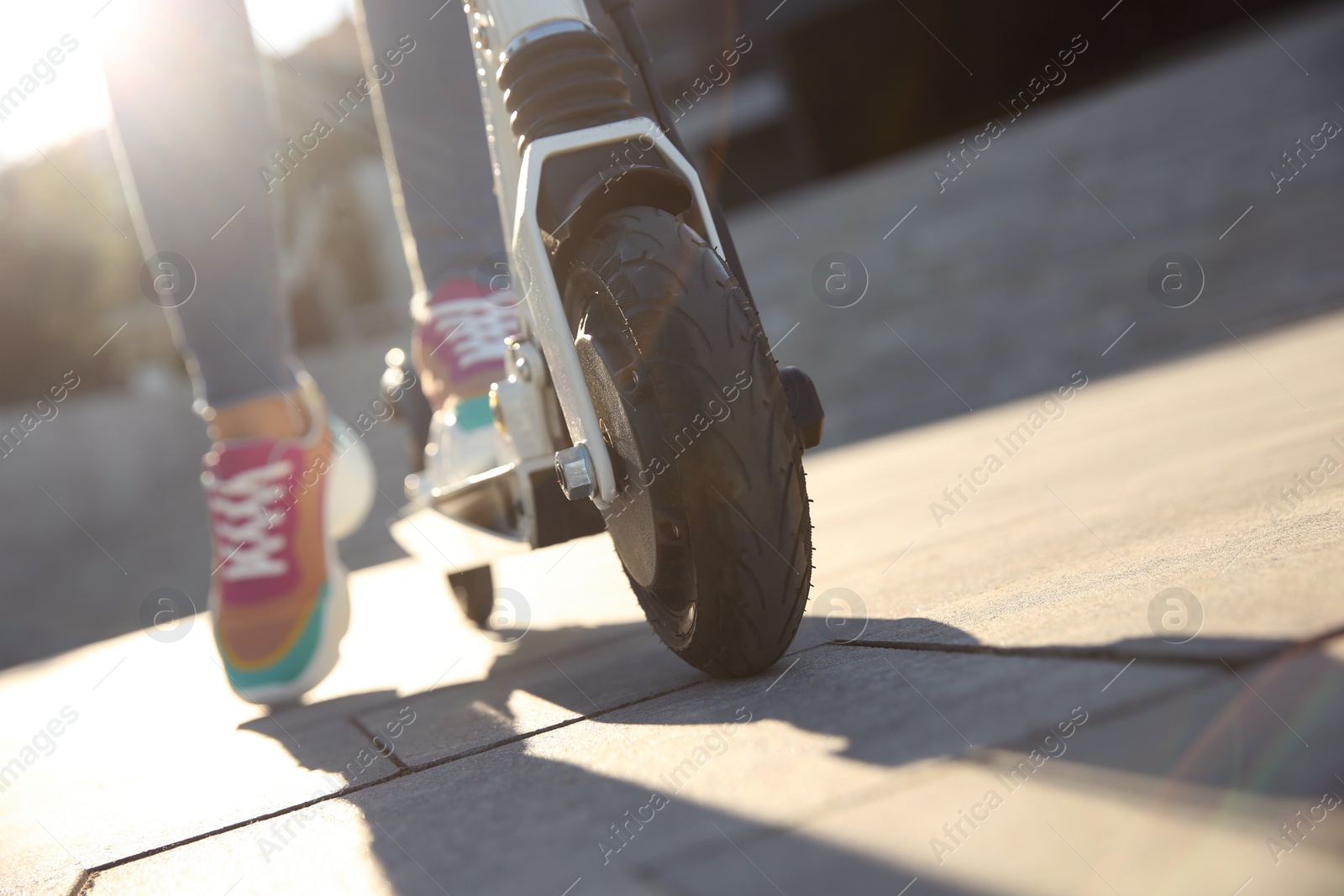 Photo of Woman riding electric kick scooter outdoors, closeup. Space for text