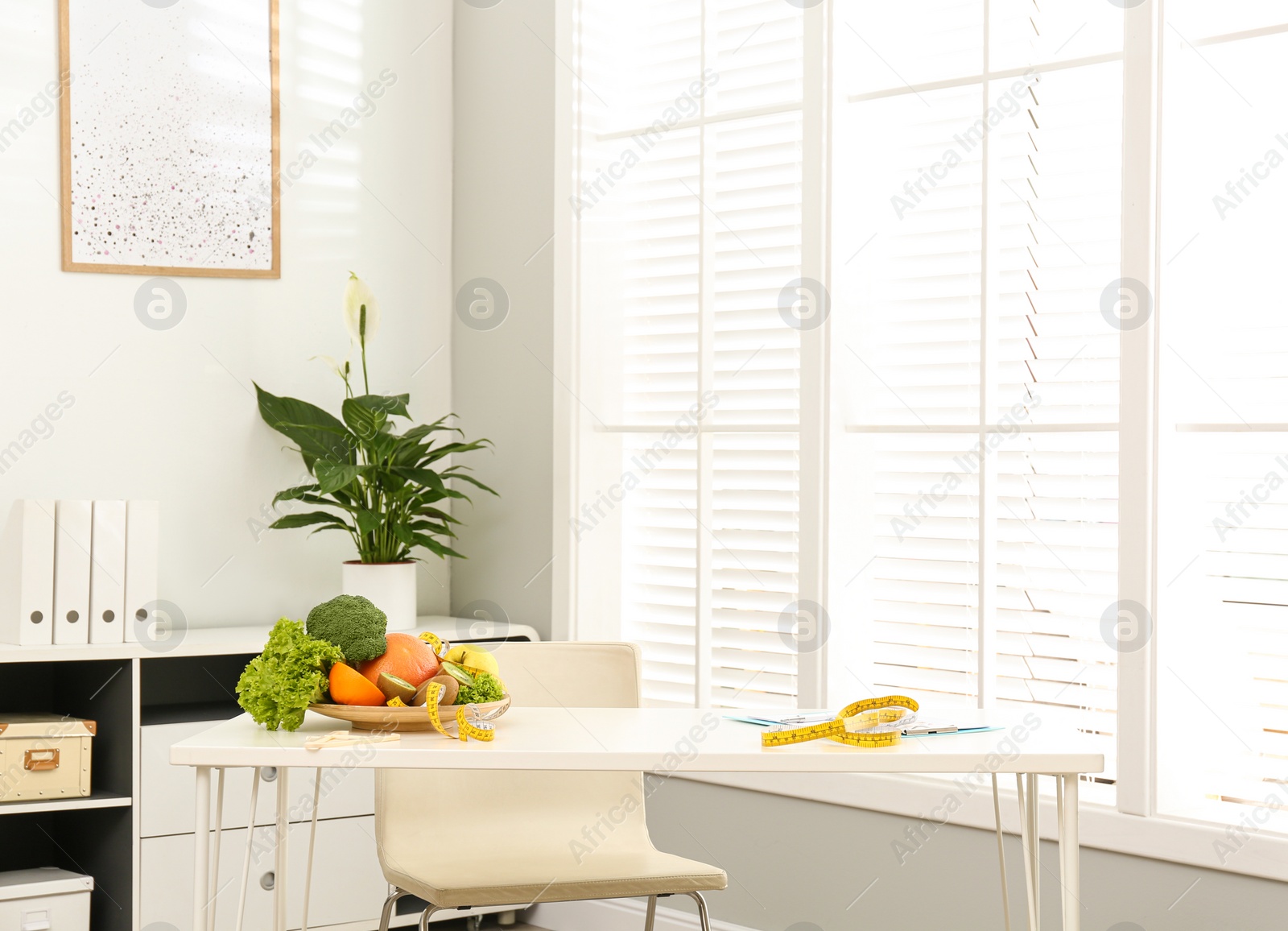 Photo of Measuring tape, vegetables and fruits on desk in nutritionist's office