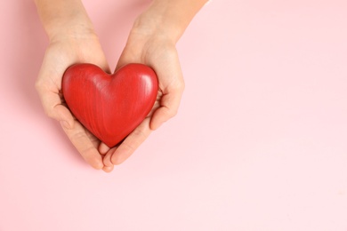 Woman holding decorative heart on color background, top view with space for text