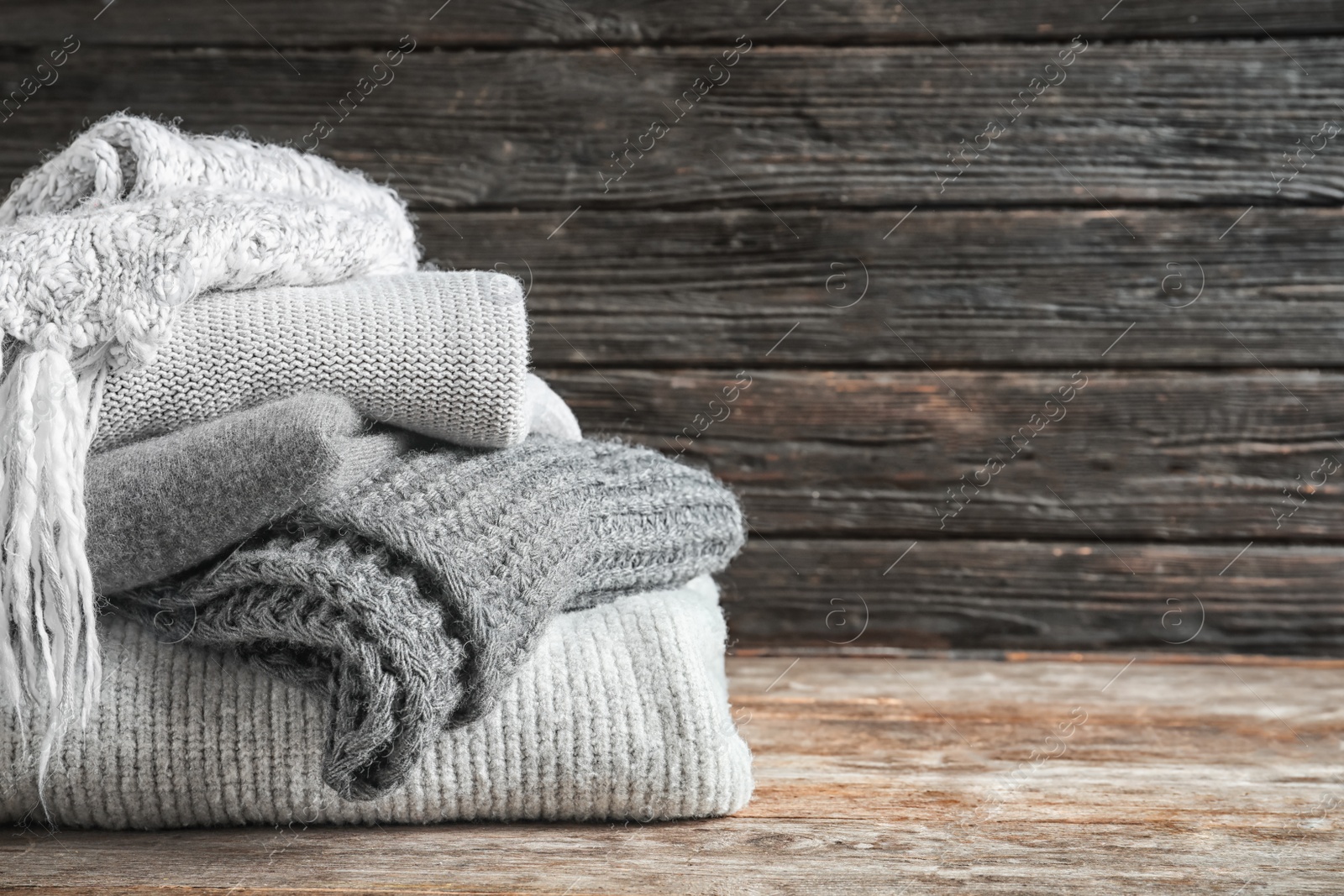 Photo of Pile of warm knitted clothes on table