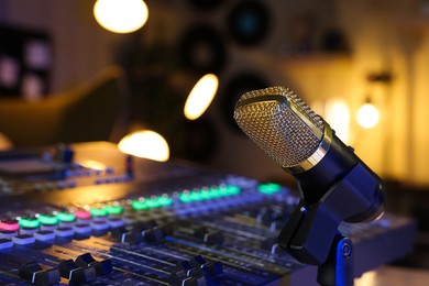 Microphone near professional mixing console in radio studio, closeup. Space for text