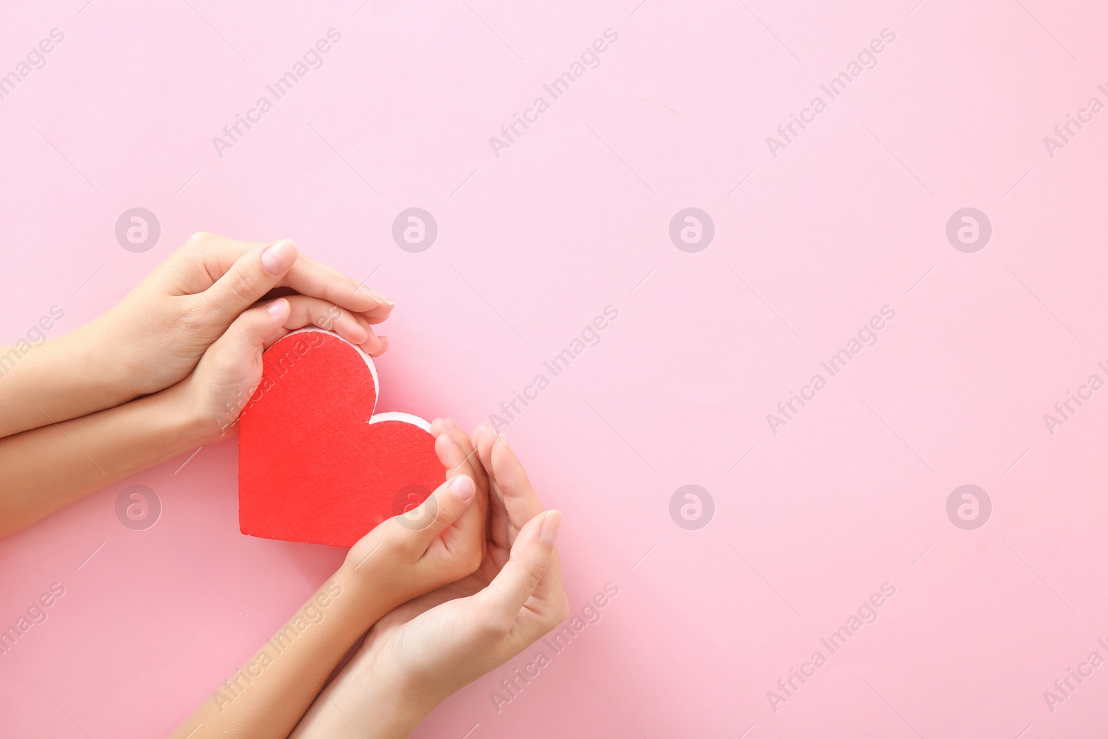 Photo of Woman and child holding red heart on color background, top view