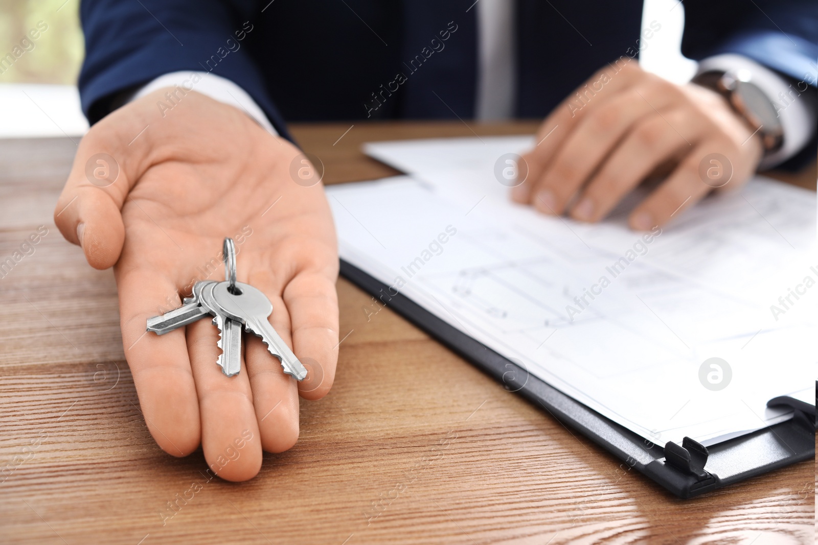 Photo of Real estate agent with keys at table in office, closeup