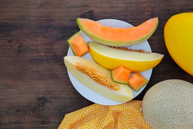 Photo of Whole and cut ripe melons on wooden table, flat lay. Space for text