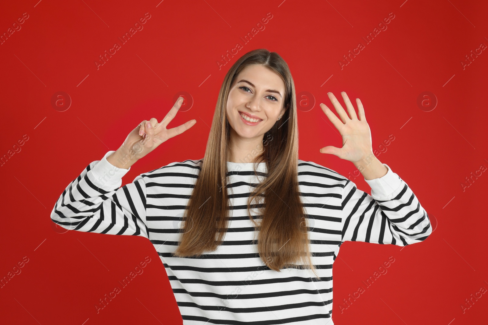 Photo of Woman showing number seven with her hands on red background