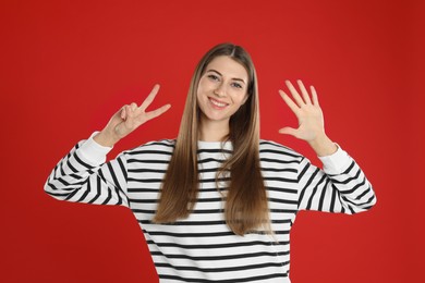 Photo of Woman showing number seven with her hands on red background