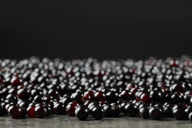 Photo of Many elderberries (Sambucus) on grey table, closeup. Space for text