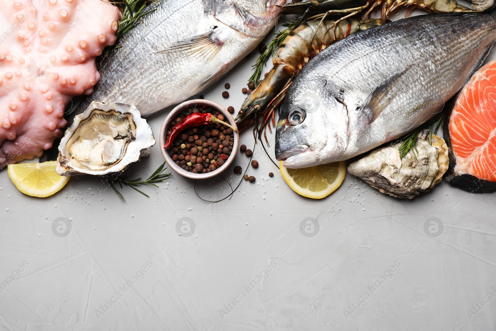 Photo of Flat lay composition with fresh raw dorado fish and different seafood, spices on light grey table. Space for text