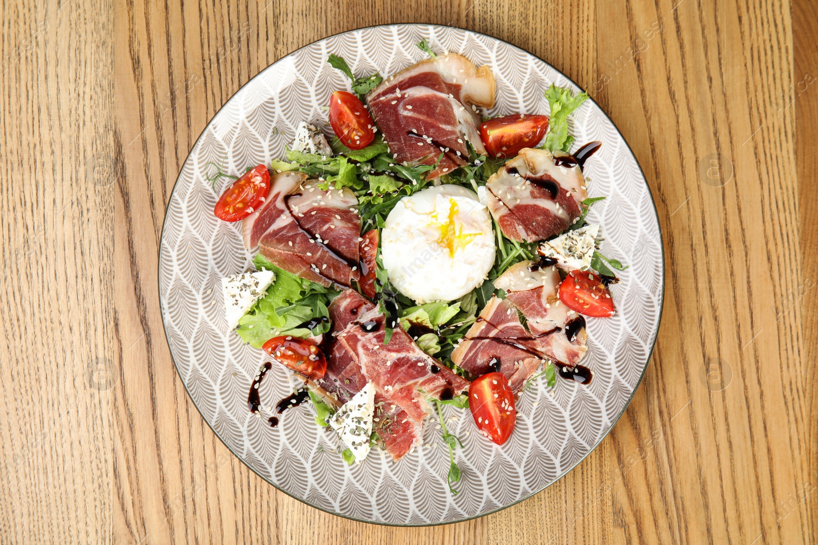 Photo of Delicious prosciutto salad with vegetables served on wooden table, top view